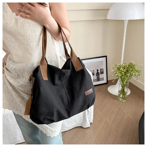 Seitenansicht einer großen schwarzen Canvas-Tragetasche mit braunen Trägern und Label