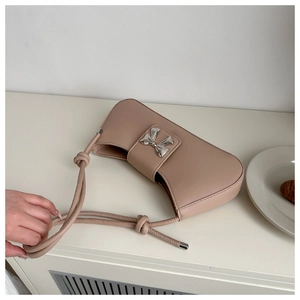 Close-up of nude pink leather bag with a silver bow buckle and knot strap detail