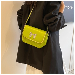 Detail of neon green crossbody bag with silver bow accent and gold metal edge trim