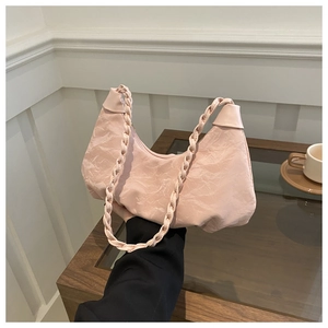 Detail of light pink ruched handbag featuring textured fabric and braided top handles