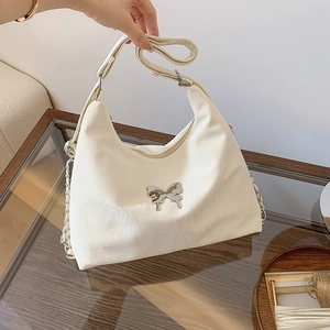 Elegant white shoulder bag with silver butterfly detail and chain strap in a lifestyle setting