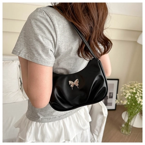 Detail of black pleated crescent bag featuring a silver fluid butterfly metal ornament