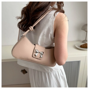 Close-up of light pink baguette bag with silver metal bow and knotted shoulder strap