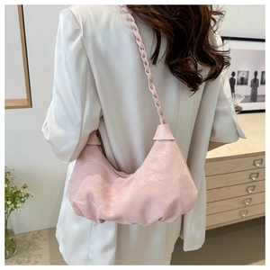 Detail of light pink crescent shoulder bag with a woven strap shown on a model
