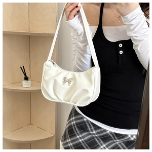 Detail of white pleated underarm bag featuring a metallic silver butterfly buckle accent