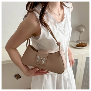 Detail of khaki leather baguette bag with silver bow buckle and knot strap detail