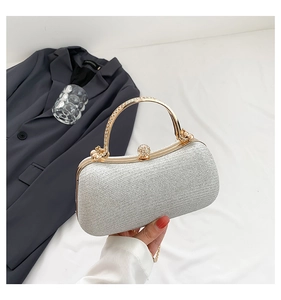 Silver sequin clutch bag with crystal clasp and gold handle held against a suit