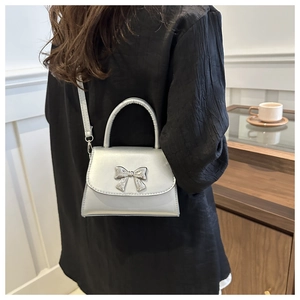 Dettaglio della mini borsa argento con fiocco in metallo 3D e tracolla regolabile