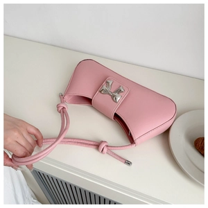 Pink leather shoulder bag with a silver metallic bow and unique knotted strap detail