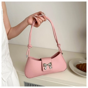Close-up of pink faux leather shoulder bag featuring a silver bow-shaped metal clasp
