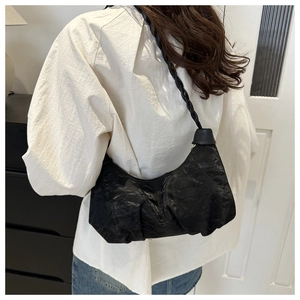 Detail of black pleated cloud bag featuring a thick braided shoulder strap for women