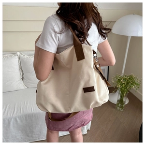 Tragebild einer cremefarbenen Canvas-Tasche mit braunen Trägern in moderner Umgebung