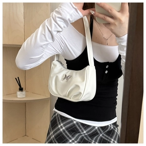 White faux leather crescent bag with silver butterfly charm shown in a lifestyle setting