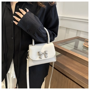 Dettaglio mini borsa squadrata bianco crema con fibbia a fiocco argento e pelle opaca