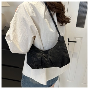 Modern black pleated hobo bag with a stylish braided shoulder strap worn by a model