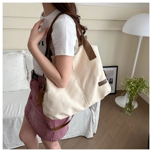 Detailed shot of beige canvas tote bag with brown handles and a stylish leather logo patch