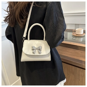 Dettaglio mini borsa bianca con fibbia a fiocco in metallo argentato e trama liscia