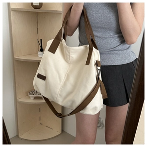 Macro detail of canvas tote bag with contrast brown straps and fashion leather label