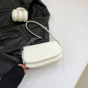 Chic white saddle shoulder bag with silver chain strap on a black leather background