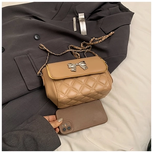 Detail of khaki quilted crossbody bag with silver bow buckle and elegant metal chain strap