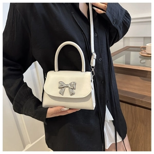 Close-up of white lychee pattern bag with silver bow detail worn by model