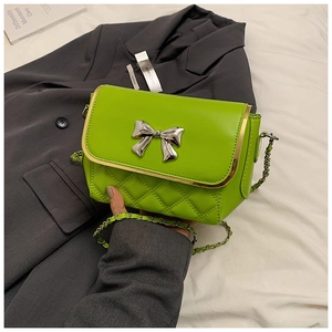 Detail of green quilted leather bag featuring a silver bow buckle and metal chain strap