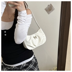 Close-up of white ruched shoulder bag featuring silver metal butterfly detail on leather