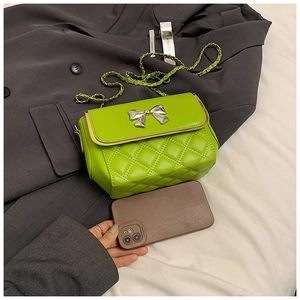 Detail of neon green quilted crossbody bag with silver bow accent and chain strap