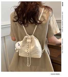 Detail of off-white pleated bucket bag with chain drawstring and plush ball pendant