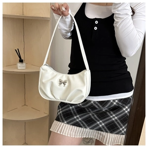 Close-up of white ruched faux leather underarm bag with silver butterfly metal accessory