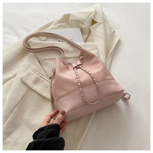 Detailed top view of pink bucket bag with silver chain and fashion logo on beige blazer