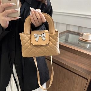 Detail shot of light brown quilted handbag with a silver bow ornament and chic handle