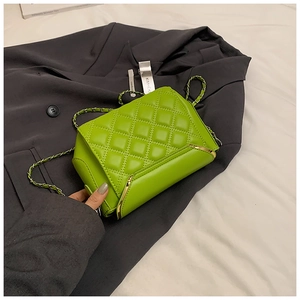 Detail of neon green quilted crossbody bag with gold metal corner and chain strap