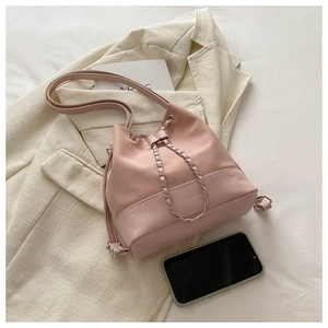 Pink drawstring bucket bag with metal chain detail and leather base on white fabric