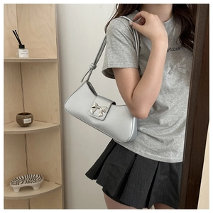 Detail of silver half-moon underarm bag with metallic bow clasp and thin strap