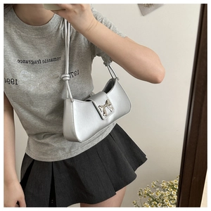 Detail of silver metallic shoulder bag featuring a decorative bow buckle and slim strap