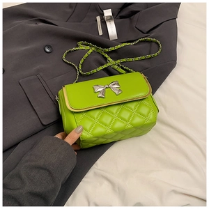 Close-up of bright green quilted crossbody bag with silver bow accent and chain strap