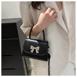 Macro di elegante borsa a tracolla nera con ornamento a fiocco argentato sul davanti