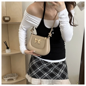Chic beige crossbody bag with golden bow detail and smooth matte leather finish