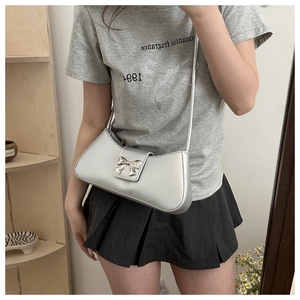 Detailed view of a silver underarm bag with a metallic bow buckle on a model
