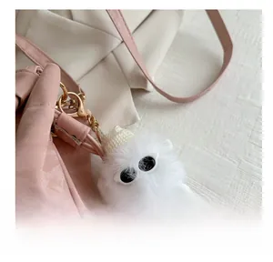 Dettaglio del charm mostro bianco peloso con occhiali da sole e corona su borsa rosa