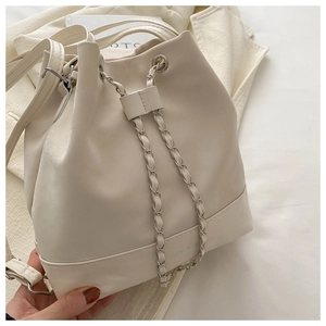 Close-up of a cream white bucket bag featuring silver chain drawstring and logo detail