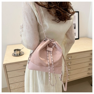 Detail of pink leather bucket bag with silver chain strap shown in minimalist interior