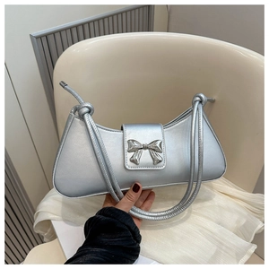 Detail of silver metallic baguette bag with 3D bow buckle and knotted double handles
