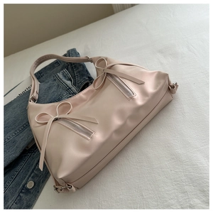 Détail du sac en cuir rose avec nœuds élégants et poches zippées argentées sur le devant
