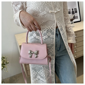Dettaglio della mini borsa a tracolla rosa chiaro con fiocco argento e trama in pelle