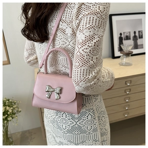 Mini borsa a tracolla rosa chic con fiocco argento indossata su una spalla