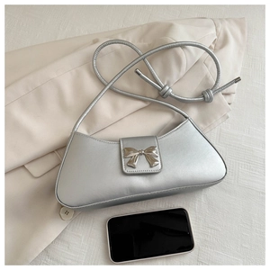 Detail of silver square underarm bag with metal bow buckle and phone for size reference