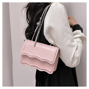 Détail du sac bandoulière rose avec rabat ondulé, chaîne argentée et logo embossé
