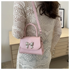 Borsa a tracolla rosa con fiocco metallico argento indossata da una modella in abito bianco